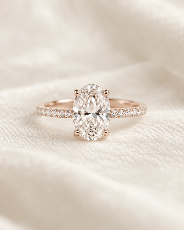 An oval diamond engagement ring with a pavé band in rose gold