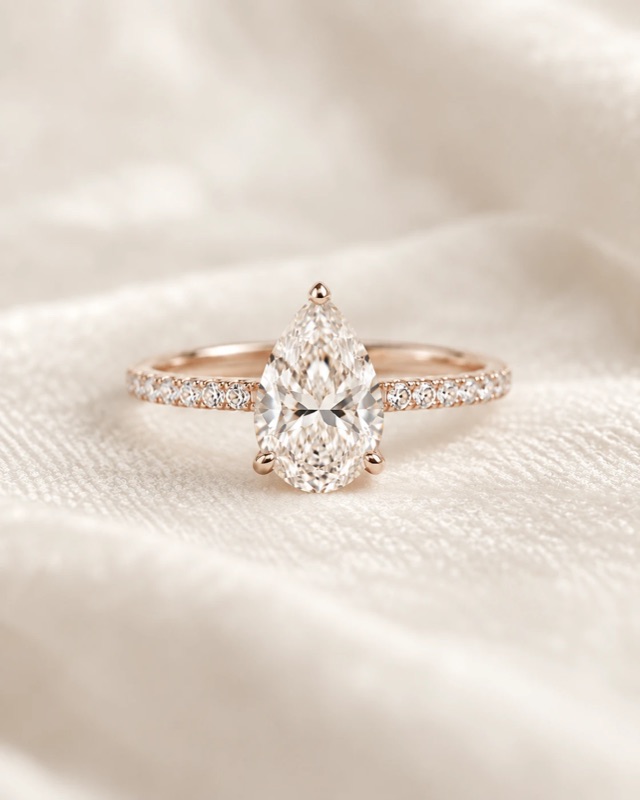 A pear-shaped diamond engagement ring with a pavé band in rose gold