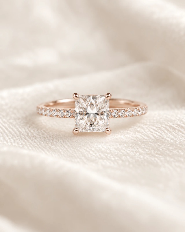 A princess-cut diamond engagement ring with a pavé band in rose gold